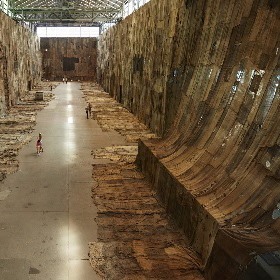 Photo of Biennale artwork, large installation of hung up old sheets and pieces of material light brown colours
